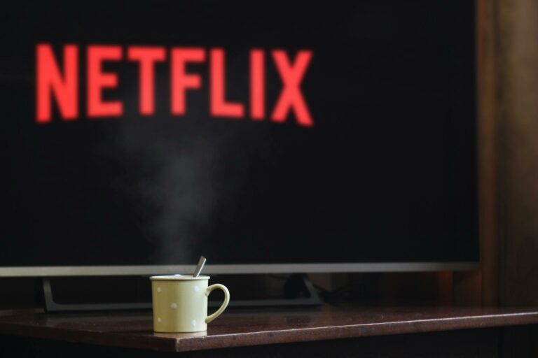 A steaming mug on a table in front of a TV displaying Netflix, creating a cozy indoor atmosphere.